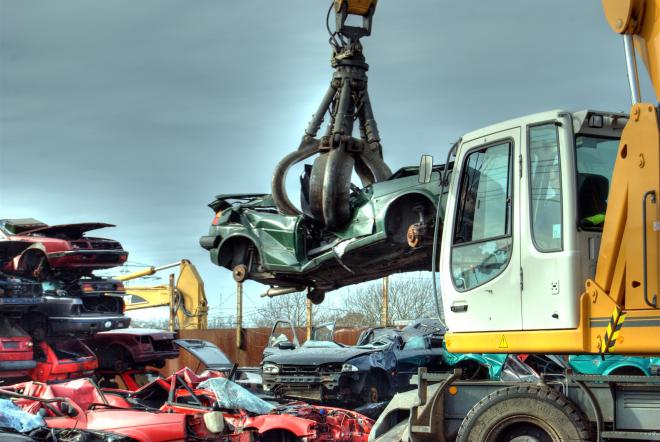 Bagger bewegt ein Auto auf einem Schrottplatz